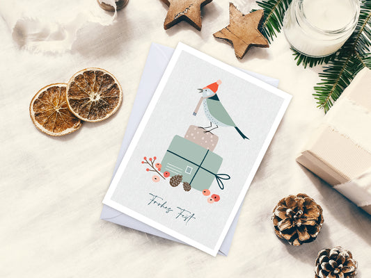 Weihnachtskarte im Scandi Nordic Stil als kleiner Postkartengruß, illustriert mit einem Vogel auf einem Geschenk und dem Wunsch nach einem "Frohen Fest". Die gedeckten Pastellfarben und der minimalistischem Nordic Design Stil zaubert dieser Weihnachtsgruß eine gemütliche Atmosphäre unter deinen Tannenbaum.