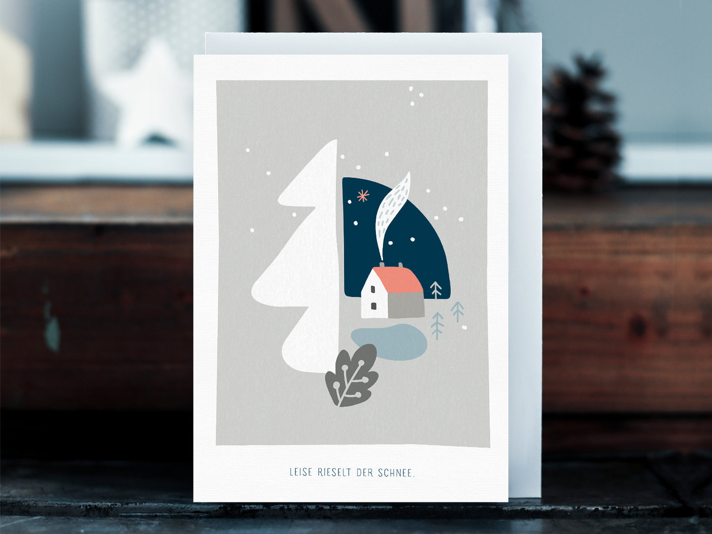 Weihnachtskarte im Scandi Nordic Stil als kleiner Postkartengruß, illustriert mit einer ruhigen, verschneiten Winterlandschaft und dem Spruch »Leise rieselt der Schnee«, in sanften Pastellfarben.  Durch die gedeckten Pastelltöne und minimalistischem Nordic Design zaubert diese Weihnachtskarte eine gemütliche Atmosphäre unter den Tannenbaum.